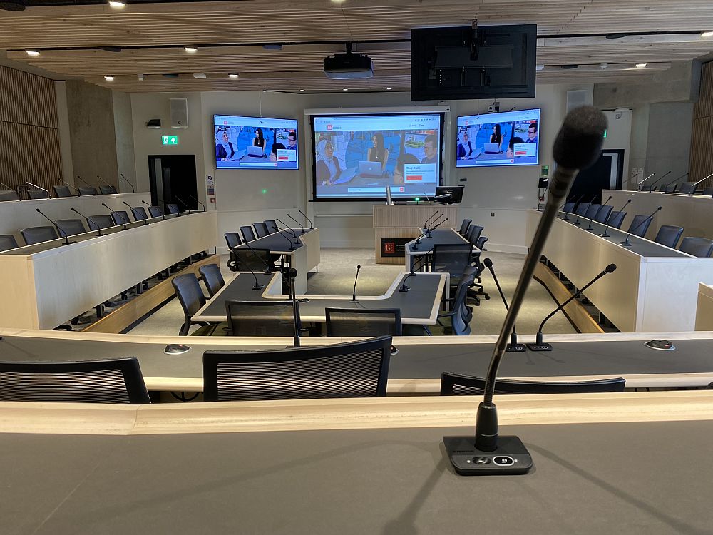 Conference room at LSE with microphones, large screens, and U-shaped seating.