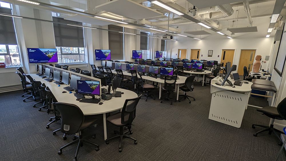  A modern seminar room with rows of chairs facing a lectern and projector screen.