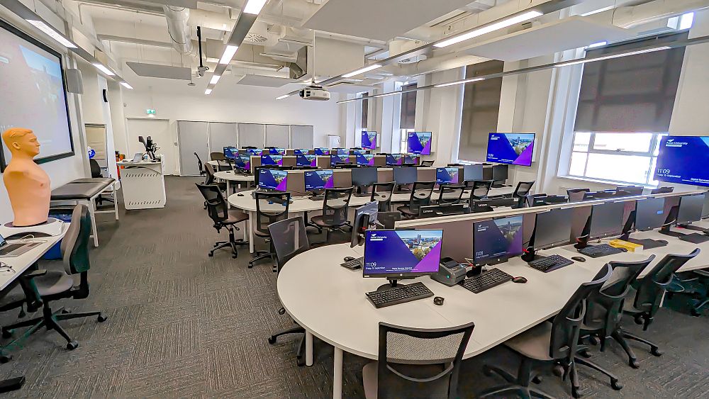  A modern seminar room with rows of chairs facing a lectern and projector screen.